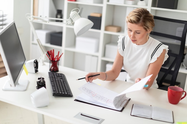 A young blonde girl sits at a computer desk in the office