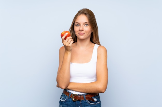 Young blonde girl with an apple over isolated wall