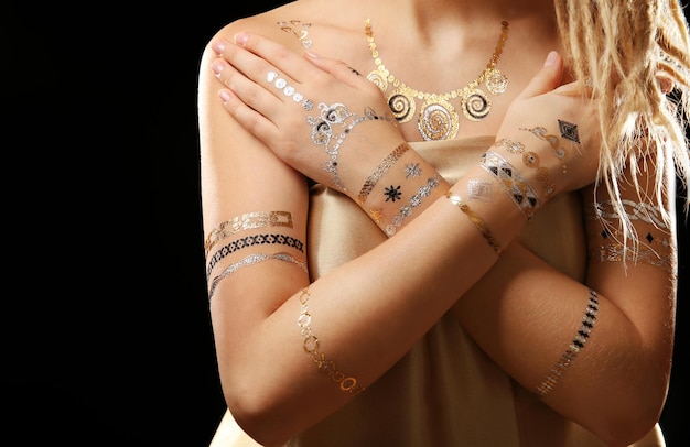 Young blonde girl with golden and silver flash tattoo on black background