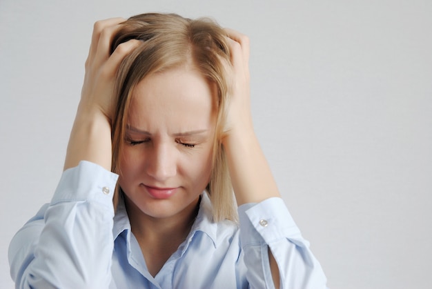 Young blonde girl with headache holds her head