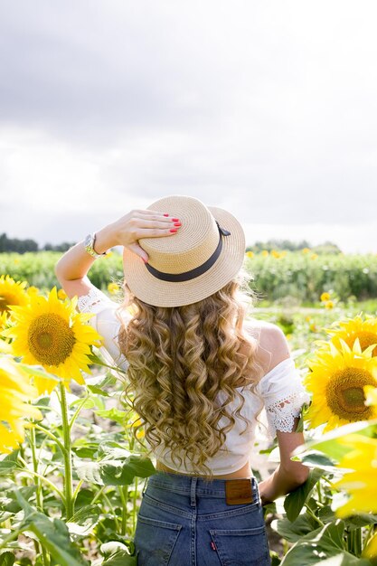 Foto giovane ragazza bionda con i capelli lunghi e ricci in un campo di girasoli