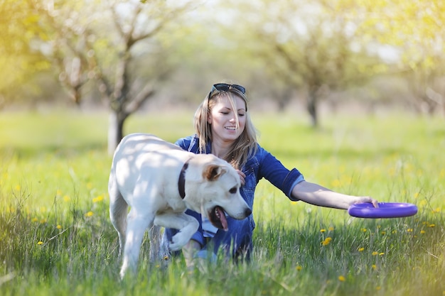 Photo young blonde is playing with a labrador on the grass in the spring.