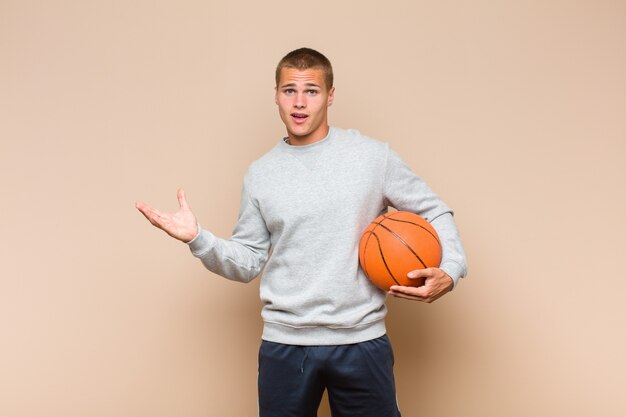 Young blonde man feeling happy, surprised and cheerful, smiling with positive attitude, realizing a solution or idea