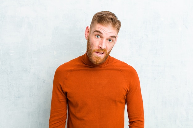 young blonde man feeling puzzled and confused with a dumb stunned expression