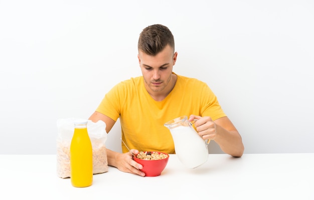 Young blonde man having breakfast