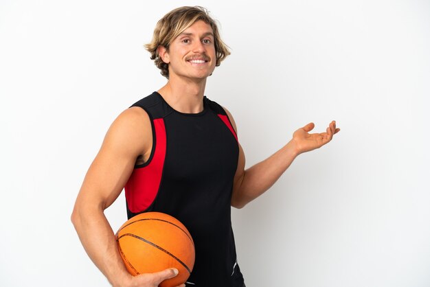 Young blonde man holding a ball of basketball isolated