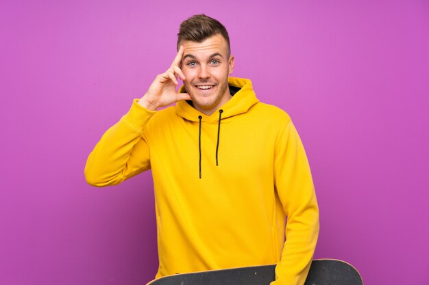 Young blonde man holding a skate with surprise and shocked facial expression