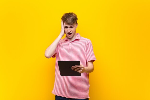 Young blonde man holding a tablet