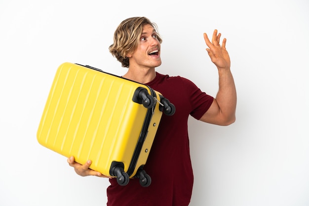 Молодой блондин, изолированные на белом фоне в отпуске с чемоданом путешествия и салютов