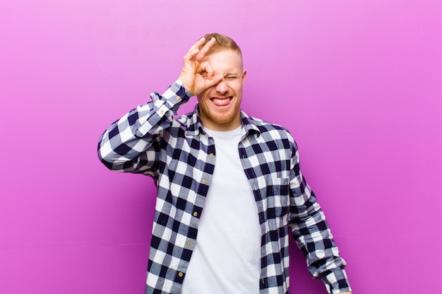 young blonde man joking and looking through the peephole