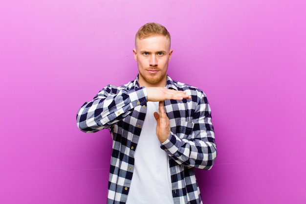 young blonde man making time out sign