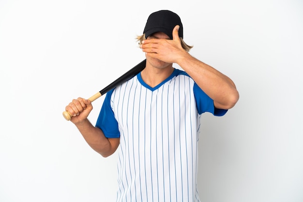 Young blonde man playing baseball isolated on white background covering eyes by hands. Do not want to see something
