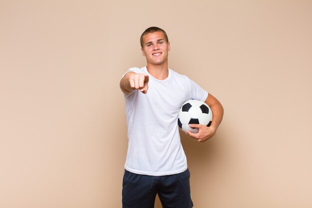 Young blonde man pointing at front with a satisfied, confident, friendly smile, choosing you