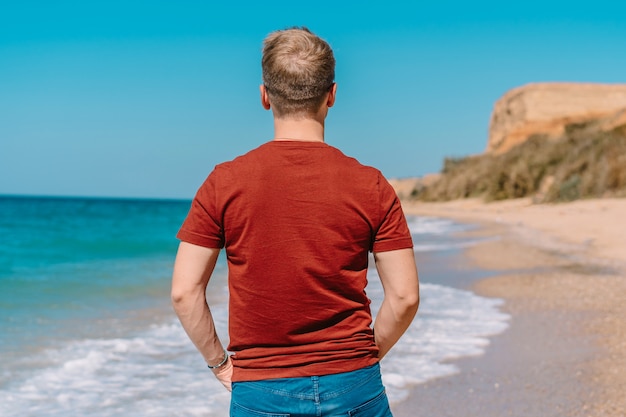 열대 해변, 하얀 모래와 푸른 바다에서 편안한 젊은 금발의 남자
