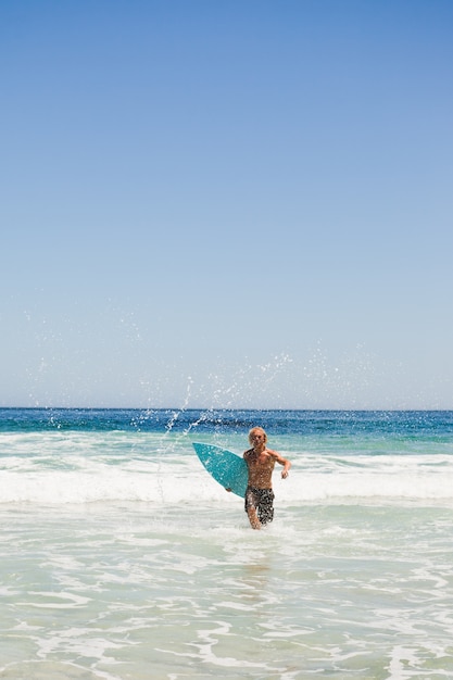 Young blonde man returning to the beach while running