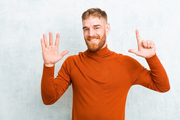 young blonde man showing number seven or seventh with hand forward counting down