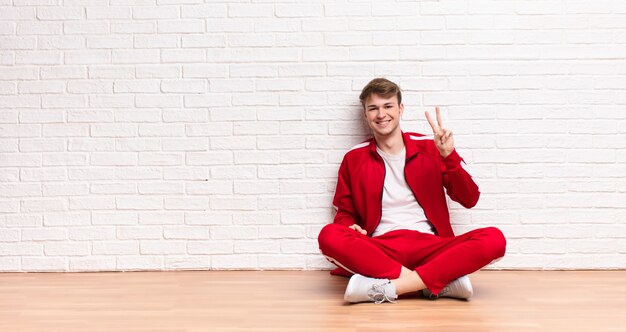 Young blonde man sitting on the floor