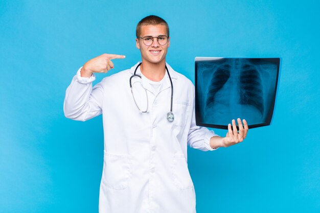 Young blonde man smiling confidently pointing to radiography