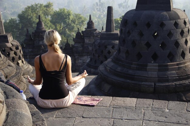 A young blonde meditating in the Borobudur temple color photo Indonesia