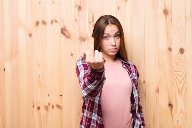 Young blonde pretty girl against wood wall