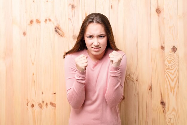 Young blonde pretty girl against wood wall