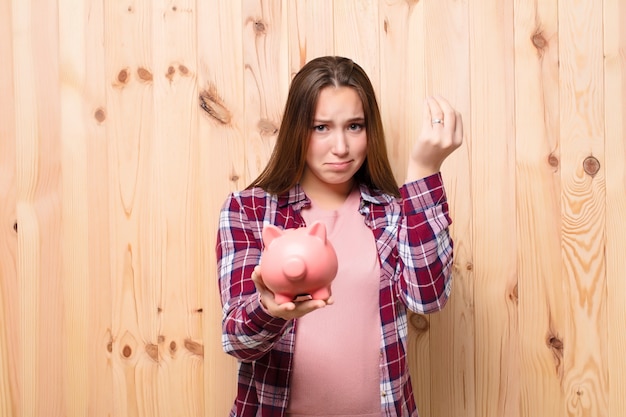 Young blonde pretty girl with a piggybank