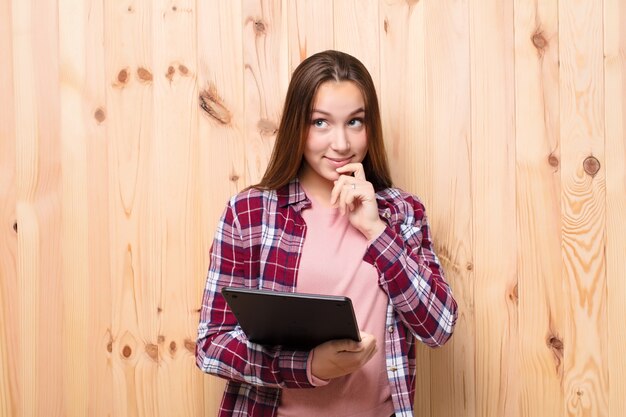 Young blonde pretty girl with a smart tablet against wood wall