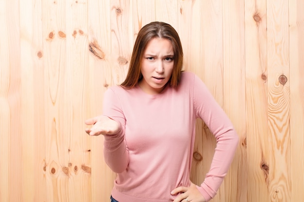 Young blonde pretty woman against wood wall