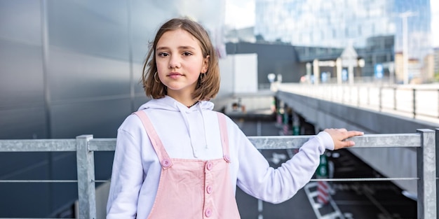 駐車場でポーズをとってピンクのドレスを着た若いブロンドの女子高生