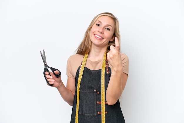 Photo young blonde seamstress woman isolated on white background doing coming gesture