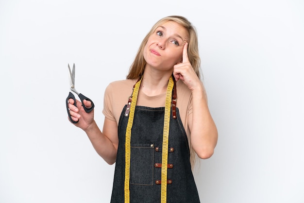 Young blonde seamstress woman isolated on white background having doubts and thinking