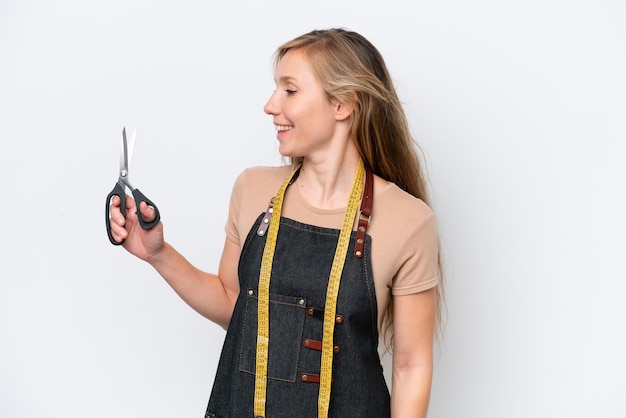 Young blonde seamstress woman isolated on white background looking side