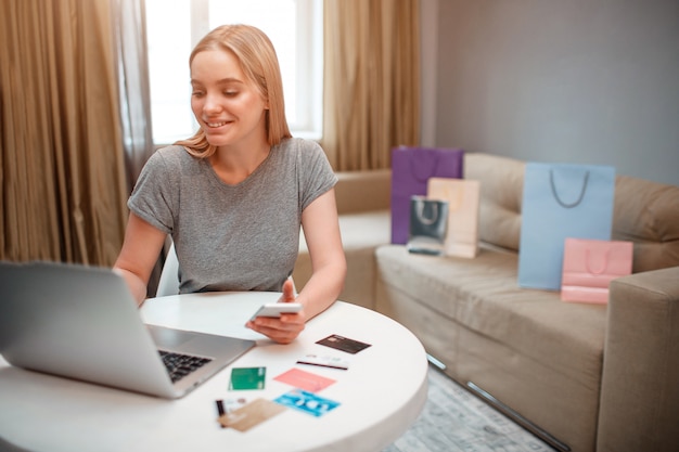 Young blonde shopper happy about big discounts while sitting at the table