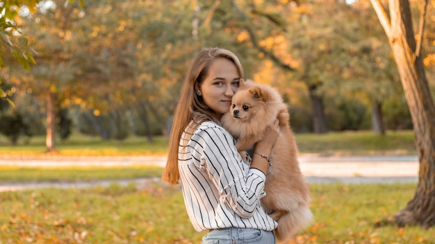 A young blonde smiles and holds a dog in her arms. 