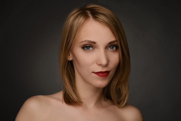 Young blonde smiling blonde woman portrait isolated on gray