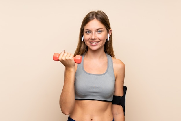 Young blonde sport girl over isolated wall making weightlifting