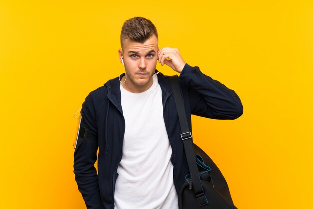 Young blonde sport man over isolated yellow wall