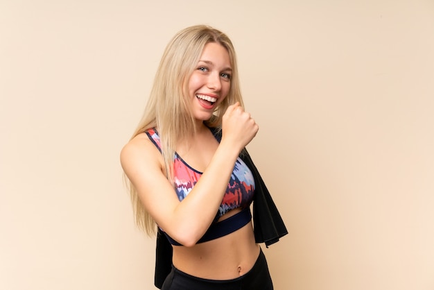 Young blonde sport woman  isolated wall celebrating a victory