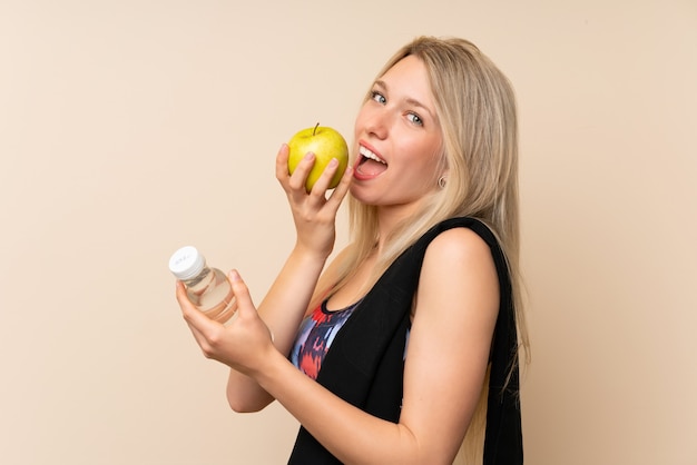 Young blonde sport woman with an apple and a bottle of water