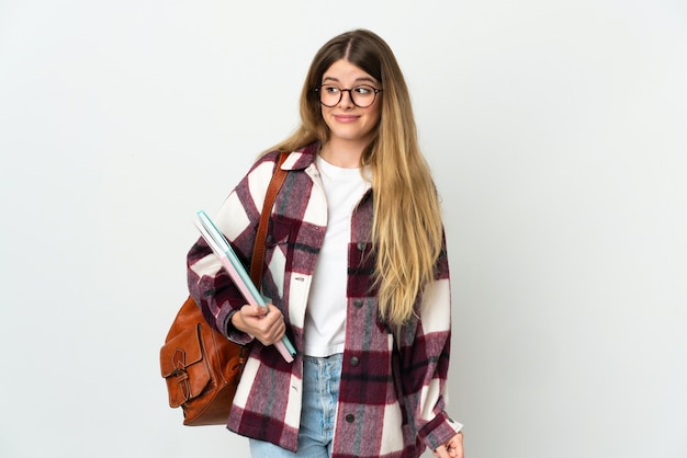 Young blonde student woman isolated making doubts gesture looking side