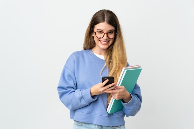 Young blonde student woman posing isolated against the blank wall