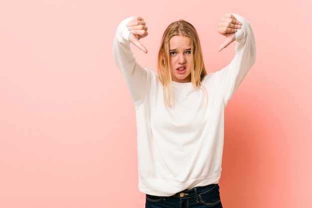 Photo young blonde teenager woman showing thumb down and expressing dislike.