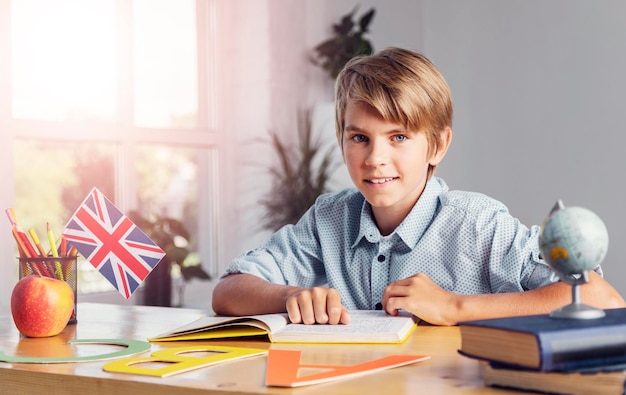 Young blonde ten years boy studying english language reading a book in light class room