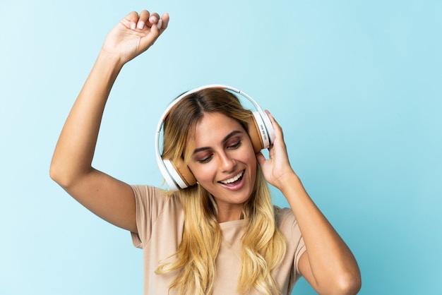 Young blonde Uruguayan on blue listening music and dancing