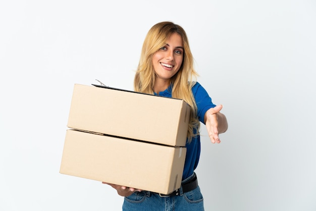 Young blonde Uruguayan delivery woman isolated on white wall shaking hands for closing a good deal