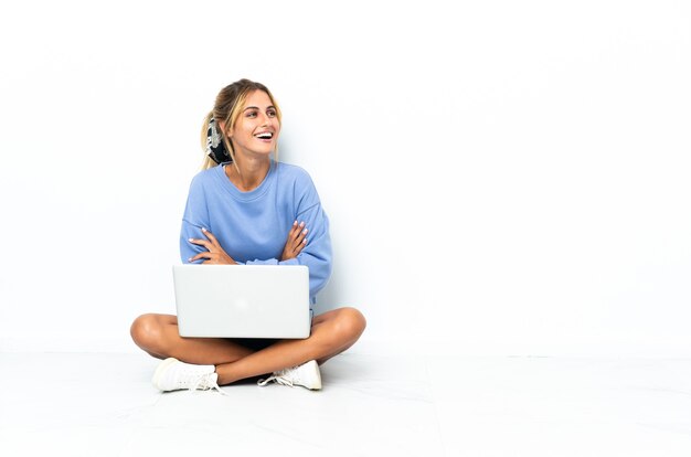 Young blonde Uruguayan girl with the laptop isolated on white happy and smiling