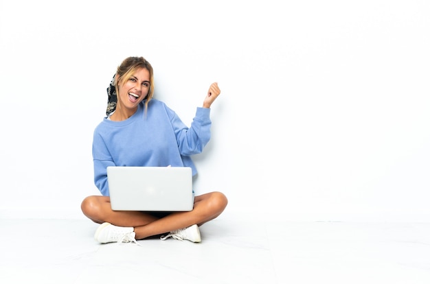 Young blonde Uruguayan girl with the laptop isolated on white wall making guitar gesture