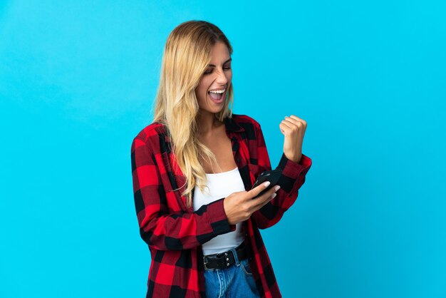 Young blonde Uruguayan woman with phone in victory position