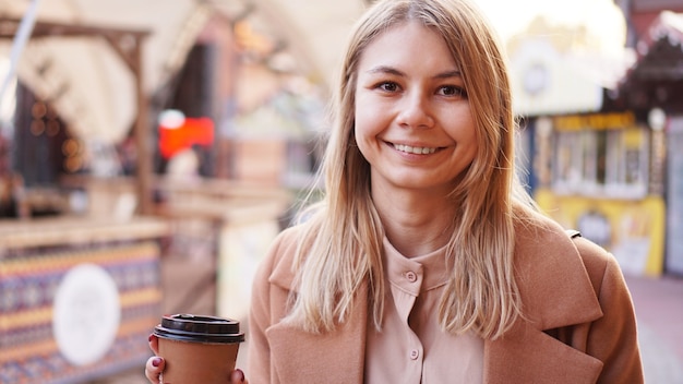 フードコートでコーヒーの女性のカップを持つ若いブロンド