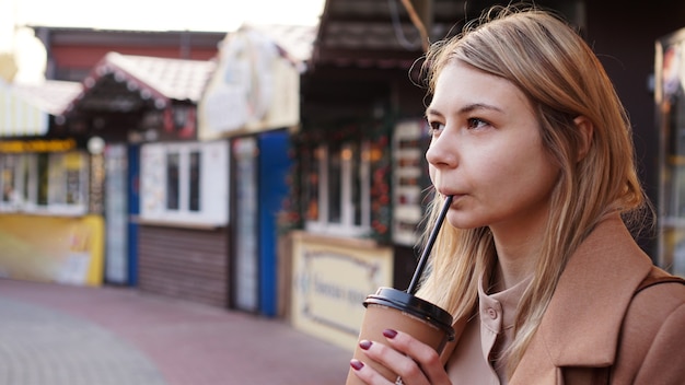 young blonde with a cup of coffee woman at the food court
